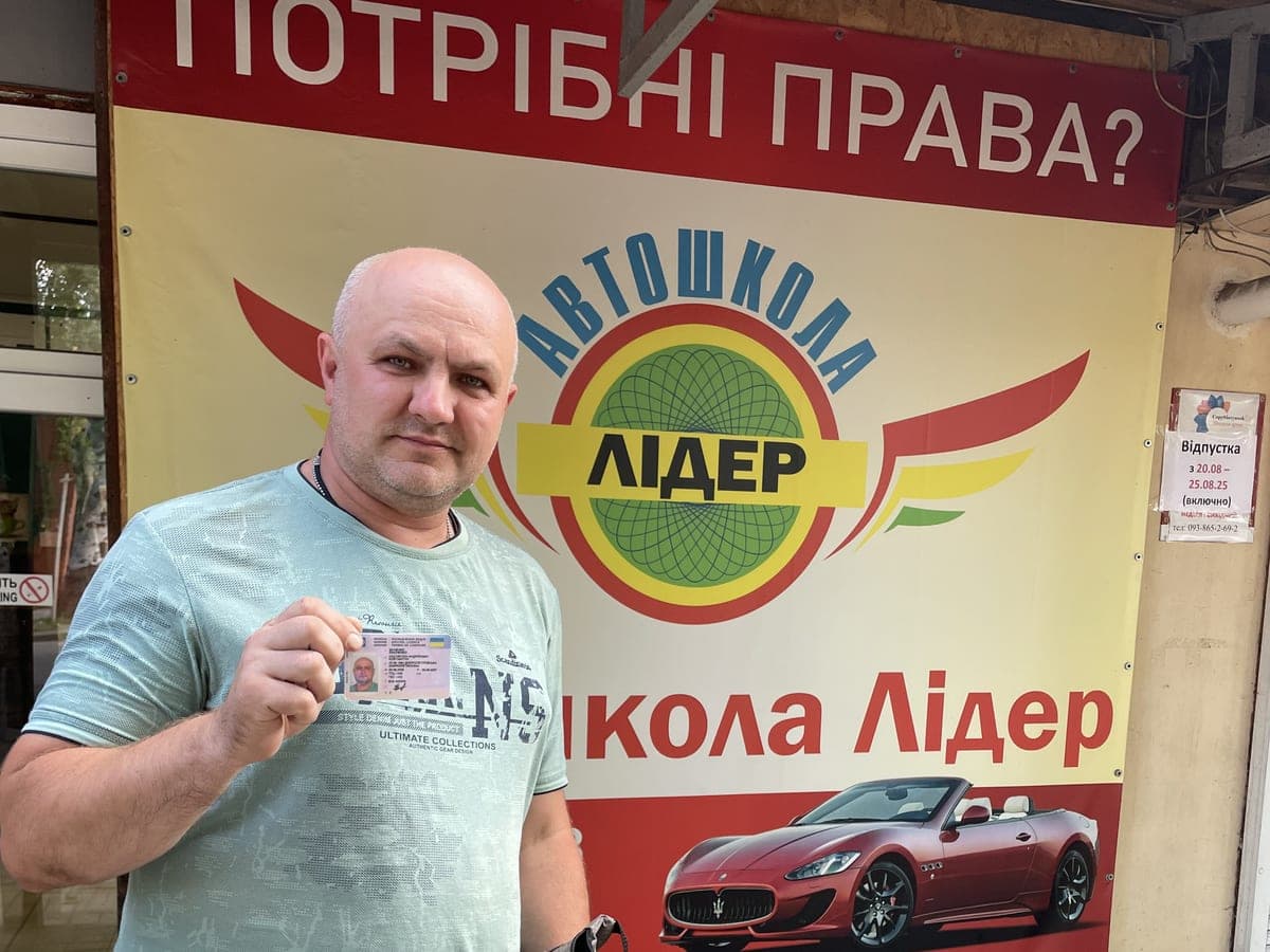 Випускник автошколи Лідер з посвідченням біля офісу